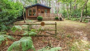 Una cabaña en un bosque con una terraza de madera y un cartel que indica que es una residencia de parque.