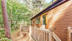 Una cabaña de madera con terraza, rodeada de árboles.