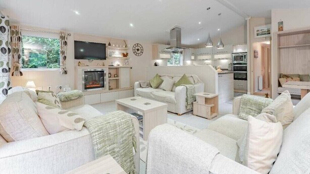 Una sala de estar moderna con chimenea, televisor y comedor, con una cocina al fondo.