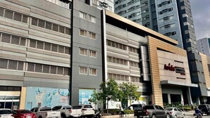 A multi-story building with a modern architectural design, featuring a prominent entrance with a sign. - Avida Towers Davao City Poblacion studio unit by darpm (Davao City)