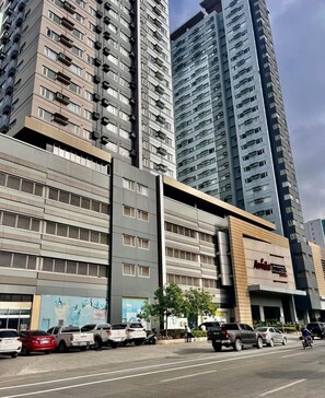 A multi-story building with a modern architectural design, featuring a prominent entrance with a sign. - Avida Towers Davao City Poblacion studio unit by darpm (Davao City)