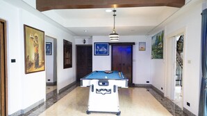 A hallway with a pool table, artwork on the walls, and a door leading to another room. - Wonderland Amethyst Luxury Villa (Muang Pattaya)