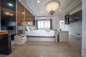 Ein modernes Hotelzimmer mit einem großen Bett, einem Nachttisch, einem Sessel, einem Fernseher und einer Chandelier.