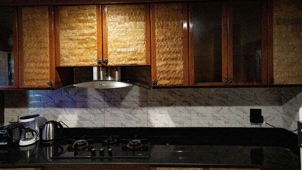 A kitchen with wooden cabinets, a gas stove, and a coffee maker. - Wonderland Amethyst Luxury Villa (Muang Pattaya)