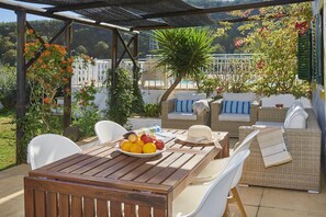 An outdoor patio with wicker furniture, a wooden table with fruit, and a pergola with plants. - CASA BRISA DO RIO, Malhada do São (Rural) (Tavira)
