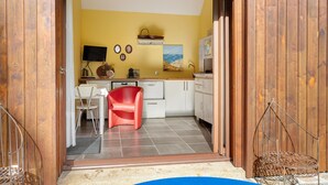 Uma cozinha com uma cadeira vermelha, uma televisão e um quadro na parede.