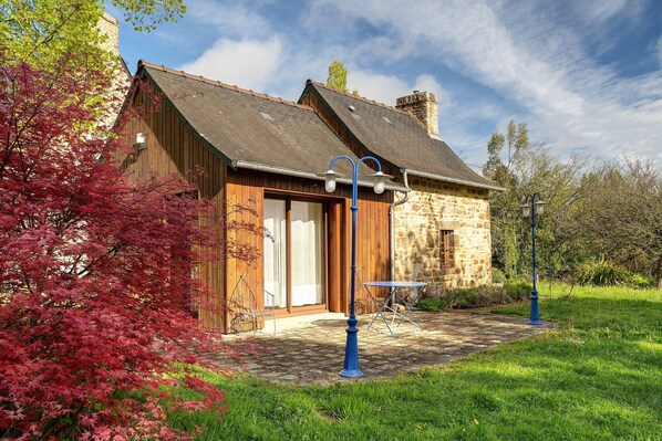 Un bâtiment rustique en pierre, doté d’une porte en bois et d’une petite table à l’extérieur.