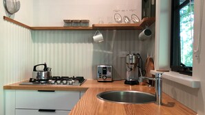 Eine moderne Küche mit Gaskochfeld, Kaffeemaschine und einem Fenster mit Blick auf Bäume.
