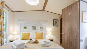 Een hotelkamer met een bed, twee nachtkastjes, een houten garderobe en een raam met gordijnen.