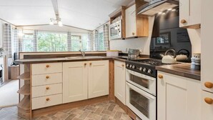 Een moderne keuken met witte kastjes, een gasfornuis en een groot raam dat voor natuurlijk licht zorgt.