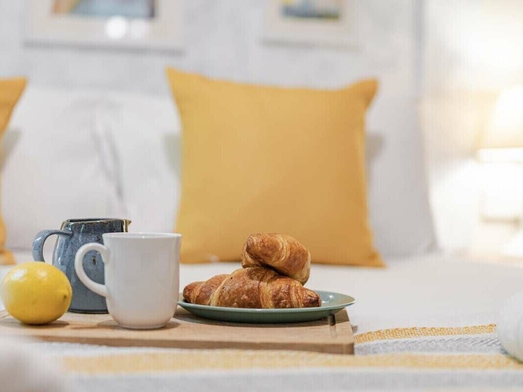 Preparación para el desayuno con cruasanes, una taza y un limón sobre una bandeja.