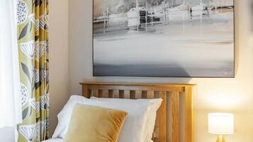 A hotel room with a bed, a nightstand, a lamp, and a large abstract painting on the wall.