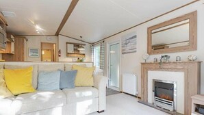 Een gezellige woonkamer met een bank, open haard en een eethoek.
