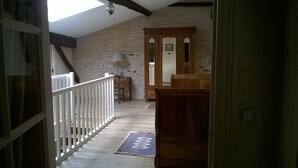 Eine Holztreppe führt zu einem Schlafzimmer auf dem Dachboden, das eine geneigte Decke und ein Dachfenster hat.