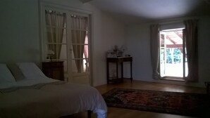 Ein Schlafzimmer mit einem Bett, einem Nachttisch, einem Tisch und einem Fenster mit Vorhängen.