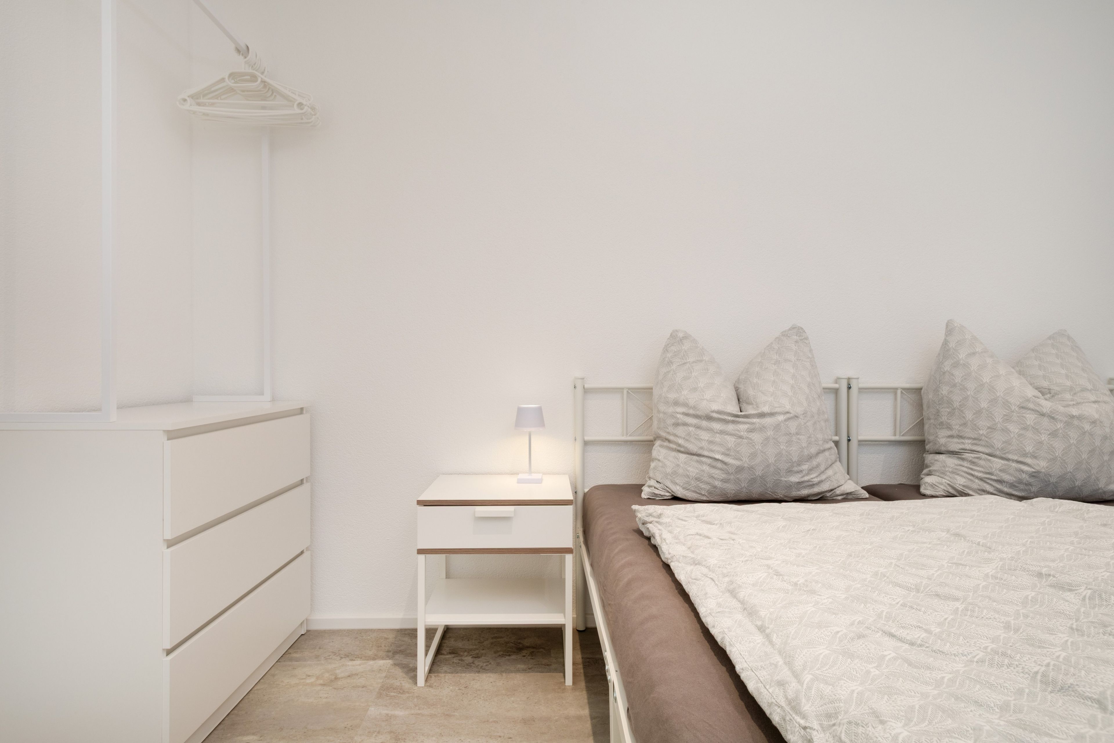 Ein schlicht eingerichtetes Schlafzimmer mit Bett, Nachttisch und Kleiderschrank.