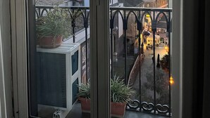 A balcony with potted plants, a view of a cityscape including a tall building, and a sign with the number 21. - Parthenope b&b (Naples)