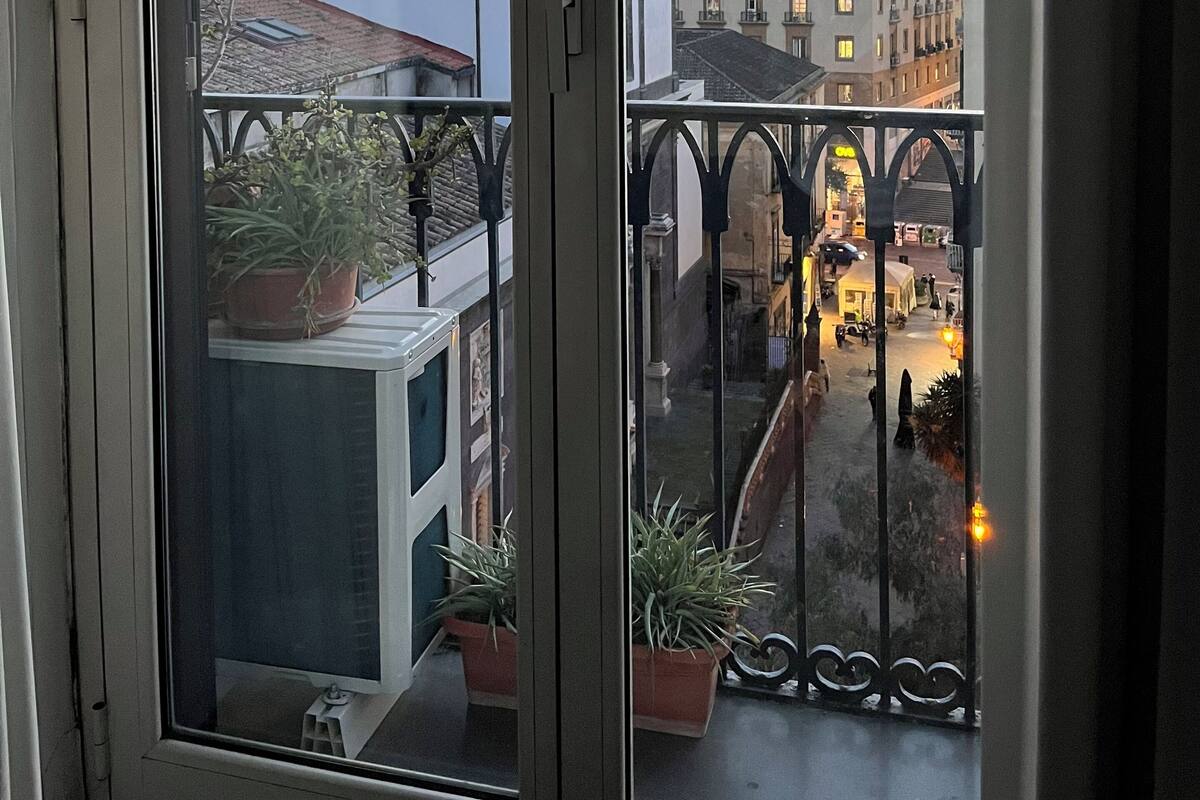 A balcony with potted plants, a view of a cityscape including a tall building, and a sign with the number 21.