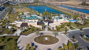 An aerial view of a resort with a large pool, palm trees, and a central building with a fountain. - 5Bd Villa Private Pool Spa at Solara Resort 1820 (Kissimmee)