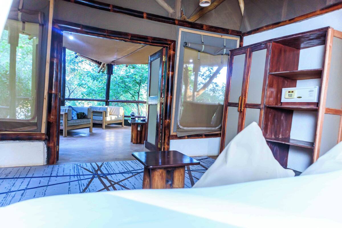 Une pièce comprenant un lit, une table en bois, un téléviseur et une étagère sur laquelle se trouve un appareil.