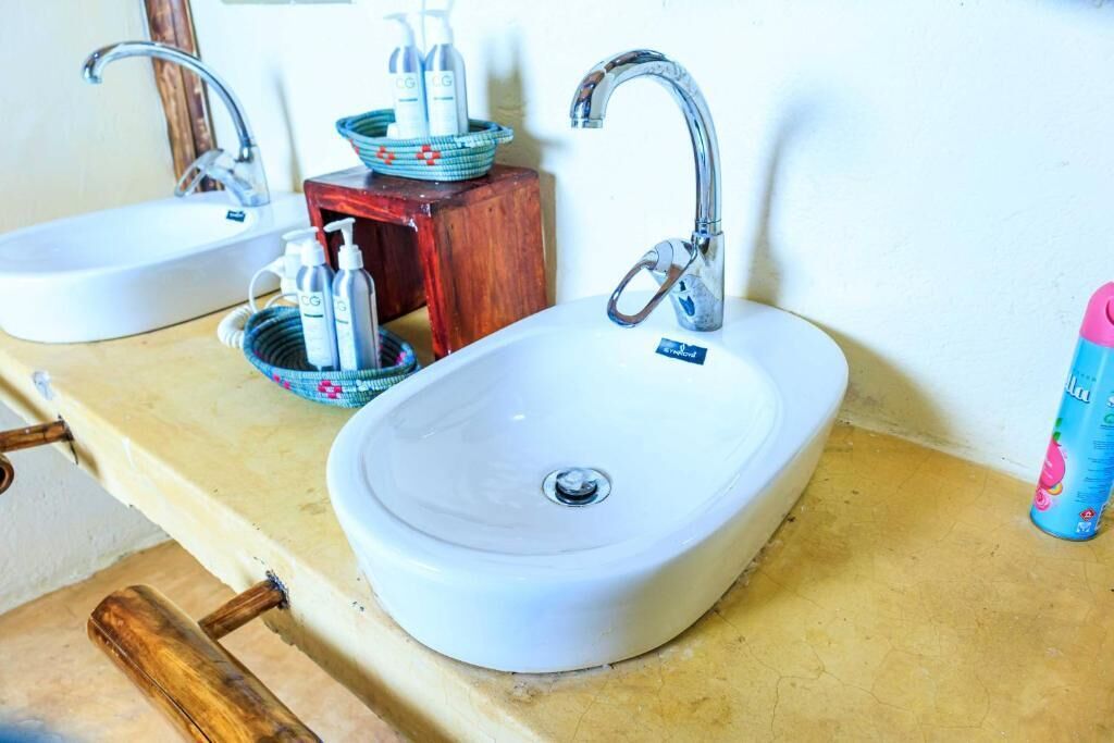 A bathroom with two sinks, a wooden stool, and a small wooden box with toiletries.