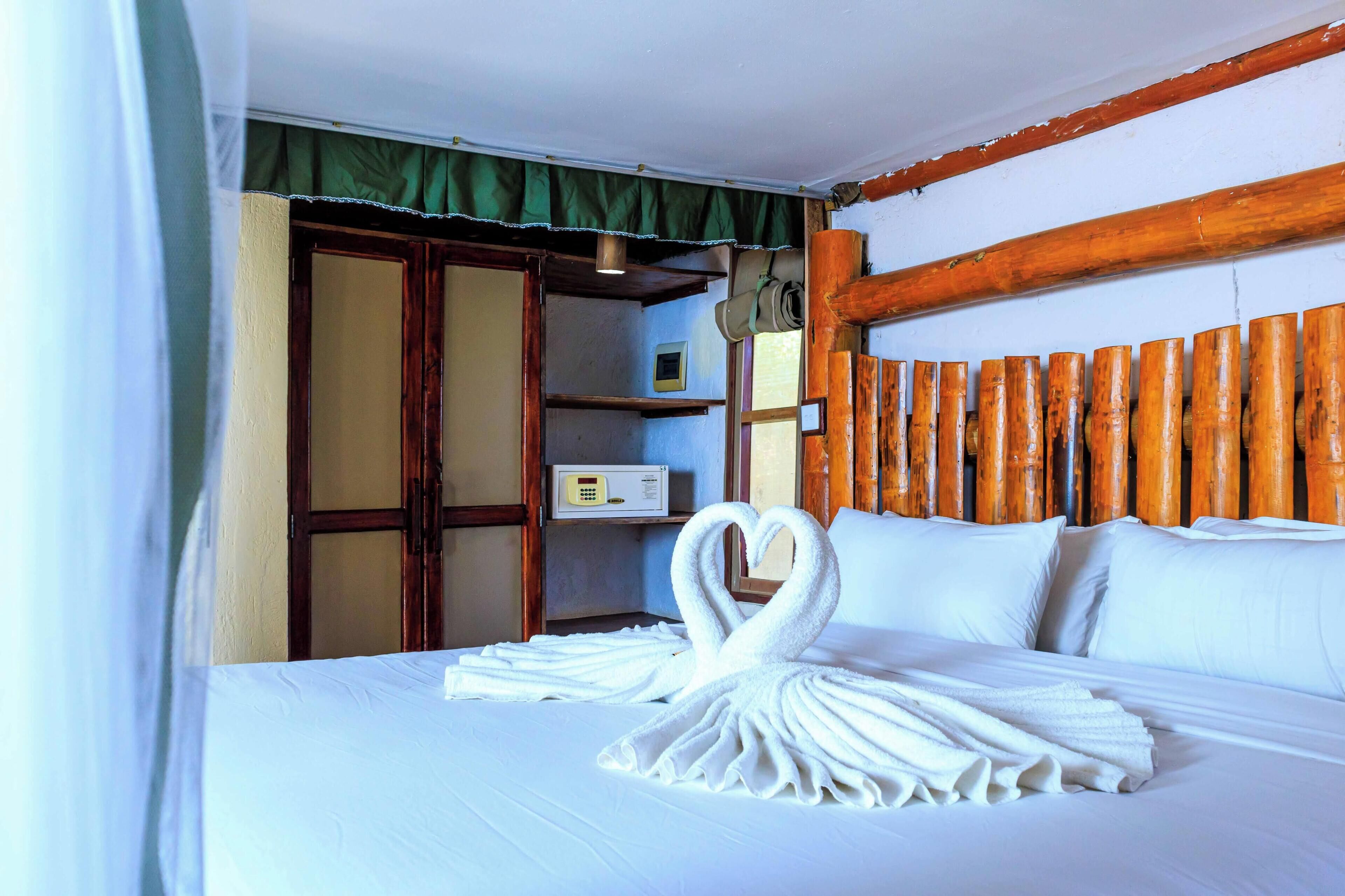 A hotel room with a bed, a wooden headboard, a wardrobe, and a bedside table.