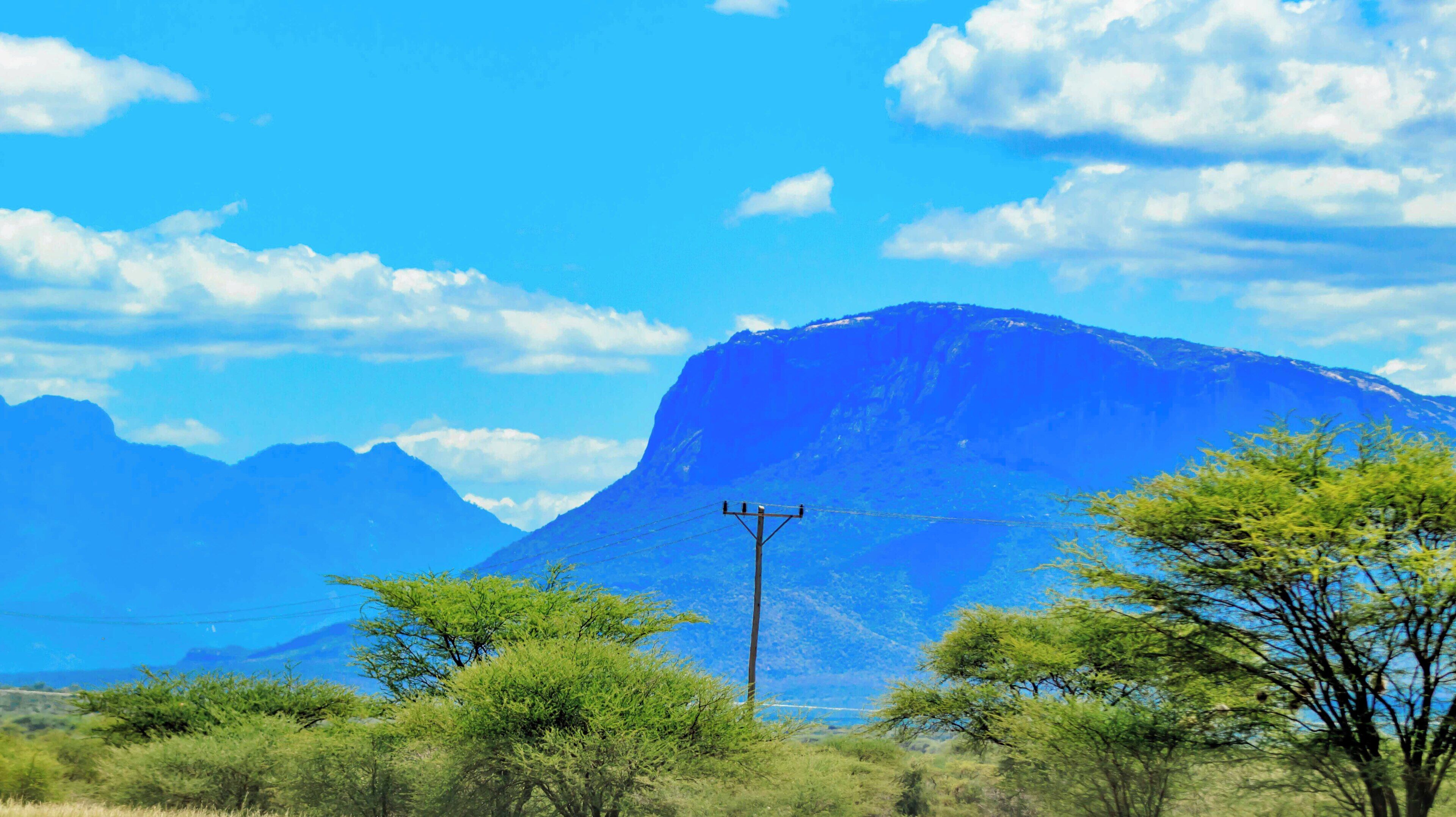 A mountainous landscape with a clear sky, power lines, and sparse vegetation.