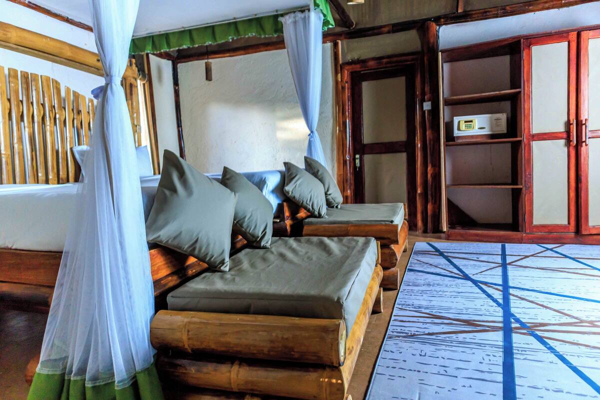 Une chambre avec un lit, une armoire en bois et une moustiquaire.