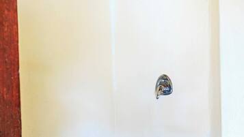 Ducha en esquina con grifo metálico, desagüe y techo de madera.
