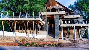 A two-story building with a wooden structure and stone base, surrounded by trees. - SAMBURU ELEPHANT LODGE (Samburu)