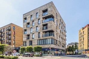 Ein modernes, mehrstöckiges Gebäude mit Backsteinfassade, großen Fenstern und Balkonen.