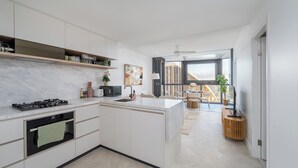Una cucina moderna con isola centrale, elettrodomestici integrati e vista su un balcone.