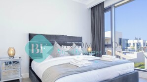 Ein modernes Hotelzimmer mit einem großen Bett, einem Nachttisch und Blick auf die Stadt.