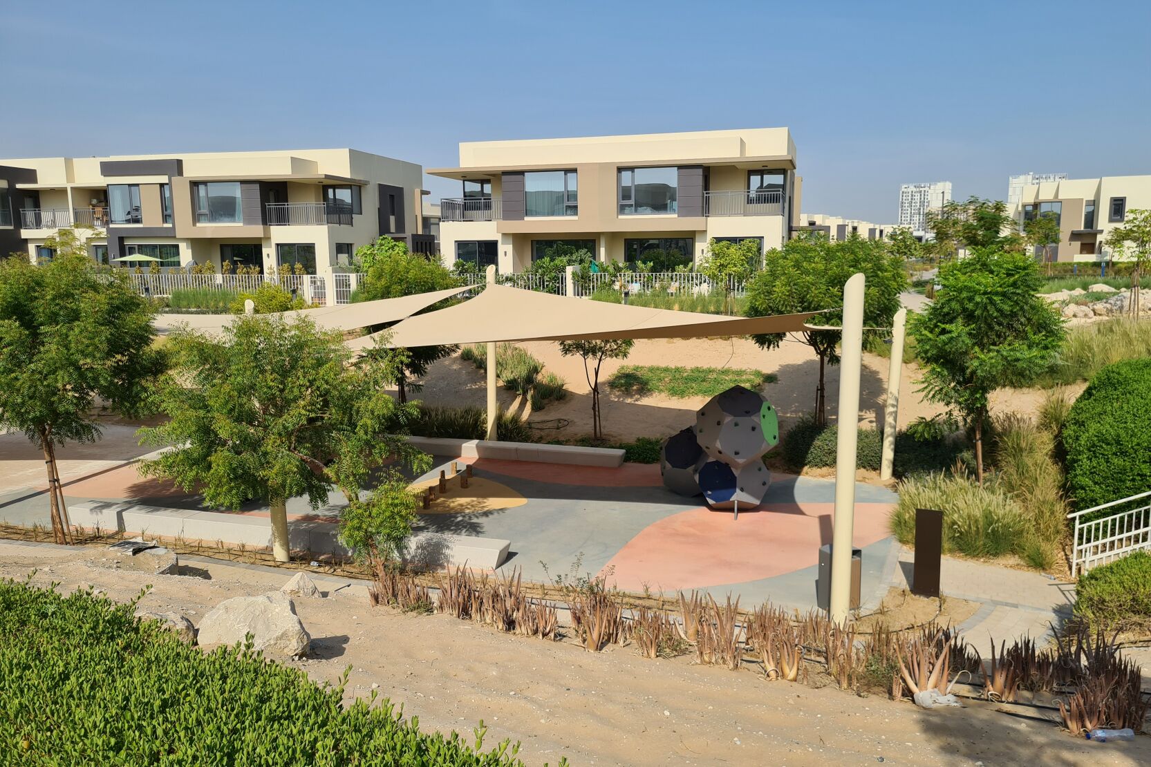 A residential area with modern buildings, a playground, and landscaped gardens.