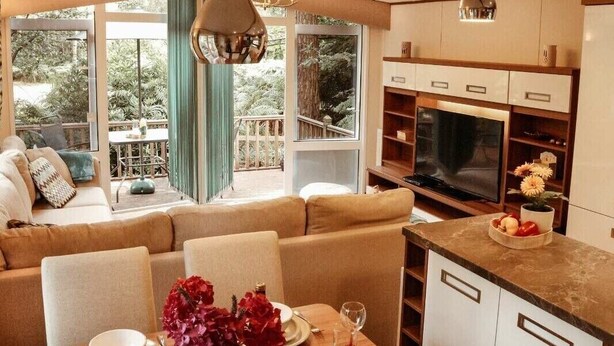 Una sala de estar moderna con sofá, mesa de comedor y zona de cocina con armarios y televisor.