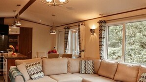 Una sala de estar moderna con un sofá modular, una mesa de centro de madera y un comedor con una cocina al fondo.
