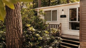 Una casa móvil con un porche delantero, un buzón y un pequeño jardín.