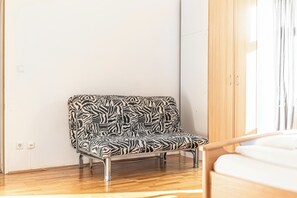 Ein Sofa mit Zebramuster in einem Raum mit Holzboden und einem Holzschrank.