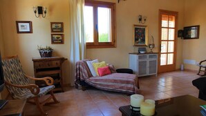 A cozy room with a bed, a wooden chair, a small table with candles, and a cabinet. - Can Colau, rural experience in Mallorca, 4 bedrooms and swimming pool (Santa Margalida)