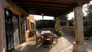 An outdoor patio with a table and chairs, stone pillars, and a covered area with a pergola. - Can Colau, rural experience in Mallorca, 4 bedrooms and swimming pool (Santa Margalida)