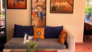 Ein Wohnzimmer mit einer Couch, dekorativen Kissen, einer Blumenvase und drei Bildern an der Wand.