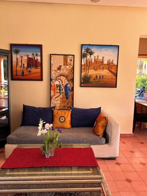 A living room with a sofa, decorative pillows, a vase with flowers, and three paintings on the wall. - Villa Essalah & Spa - Entire Private Villa with Spa, Marrakech (Marrakech)