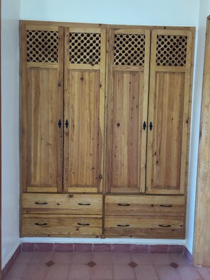 A wooden wardrobe with two drawers and two doors, each with a lattice design on the upper part.