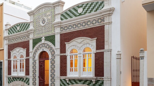 Een gebouw met een klassiek gevelontwerp, een betegeld voetpad, boogramen en een decoratieve deur.