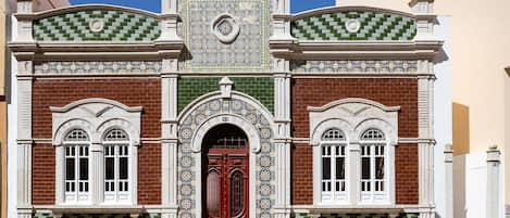 A building with a red door, white windows, and decorative tile patterns.
