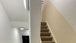 A carpeted staircase with a handrail, white walls, and a light fixture on the ceiling. - Between the Beach and the Shops (Portsmouth)