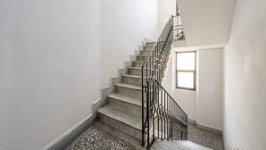 Eine Treppe mit Metallgeländer, gefliestem Boden und einem Fenster am Oberende.