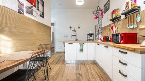 Eine moderne Küche mit Holzboden, weißen Schränken, einem Holztisch mit Stühlen und einer Pendelleuchte.
