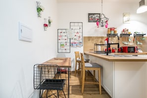 Une cuisine compacte dotée d’un îlot central en bois, d’un coin repas avec une table et des chaises, ainsi que de divers ustensiles et appareils de cuisine.