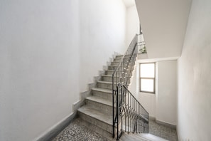 Una scala con ringhiera in metallo, pavimento piastrellato e una finestra in cima.